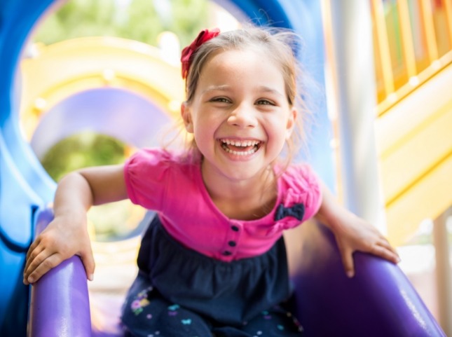 Young girl laughing on outdoor slide