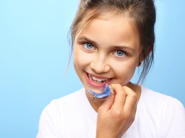 Young girl holding a blue wire retainer