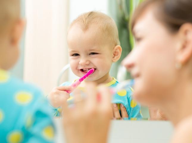 Mother and baby brushing their teeth together