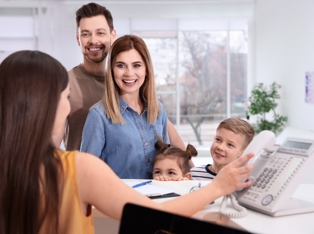 Family of four talking to dental office receptionist