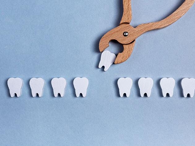 Wooden forceps grasping fake wooden tooth from a row