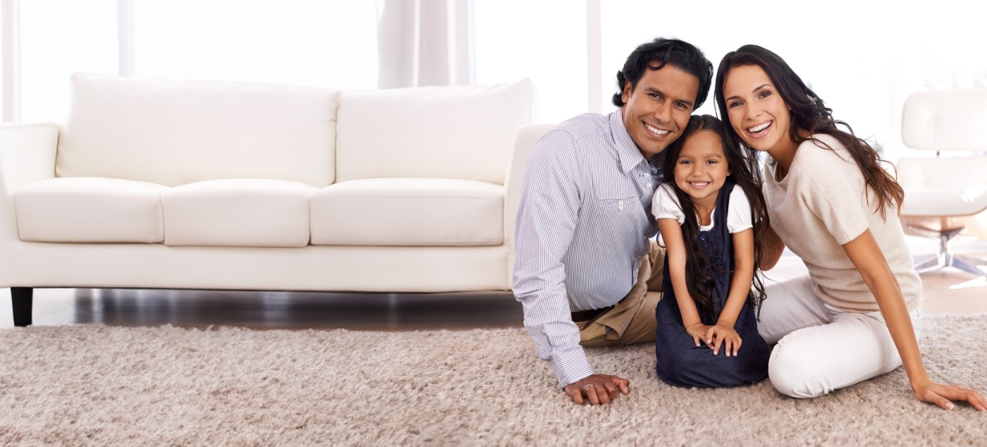 Smiling family of three sitting on living room carpet