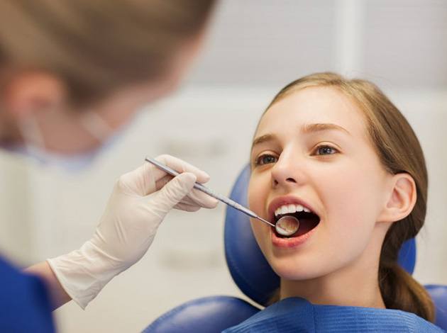 a dentist checking a teen’s mouth for oral health problems