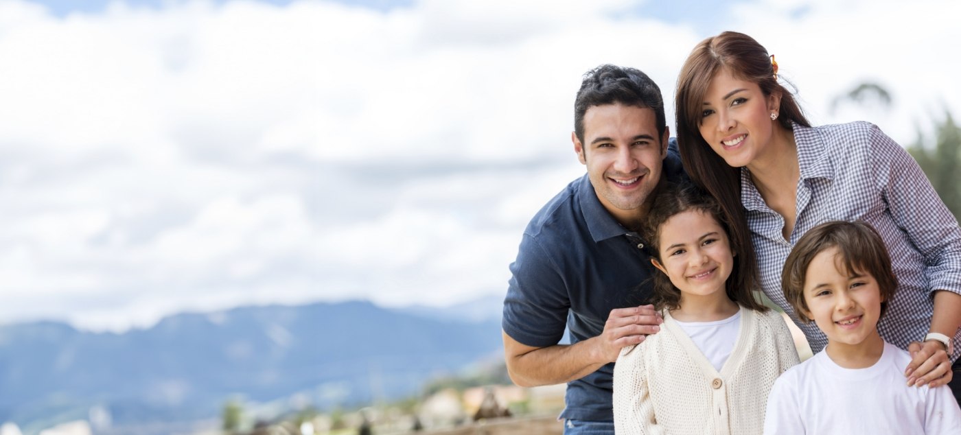 Family of four grinning outdoors
