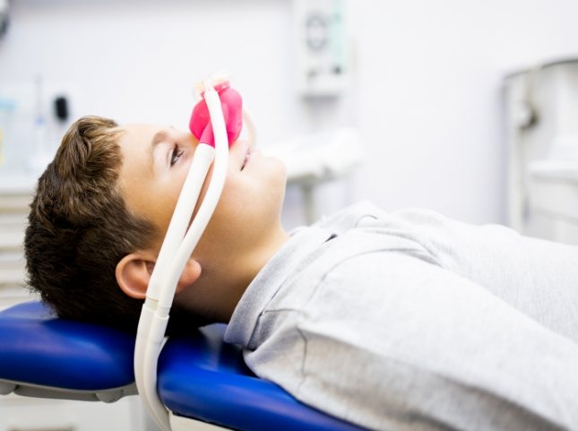 Boy laying in dental chair with nitrous oxide mask over his nose