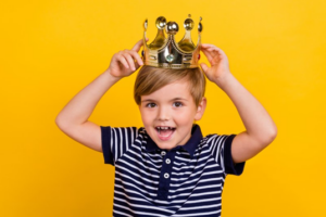 Little boy putting a crown on his head