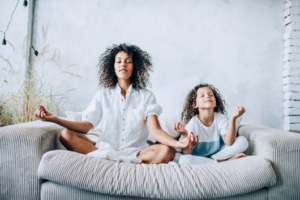 Mom and daughter in a yoga pose on the couch